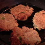 Four Tuna Patties Frying in Cast Iron Skillet